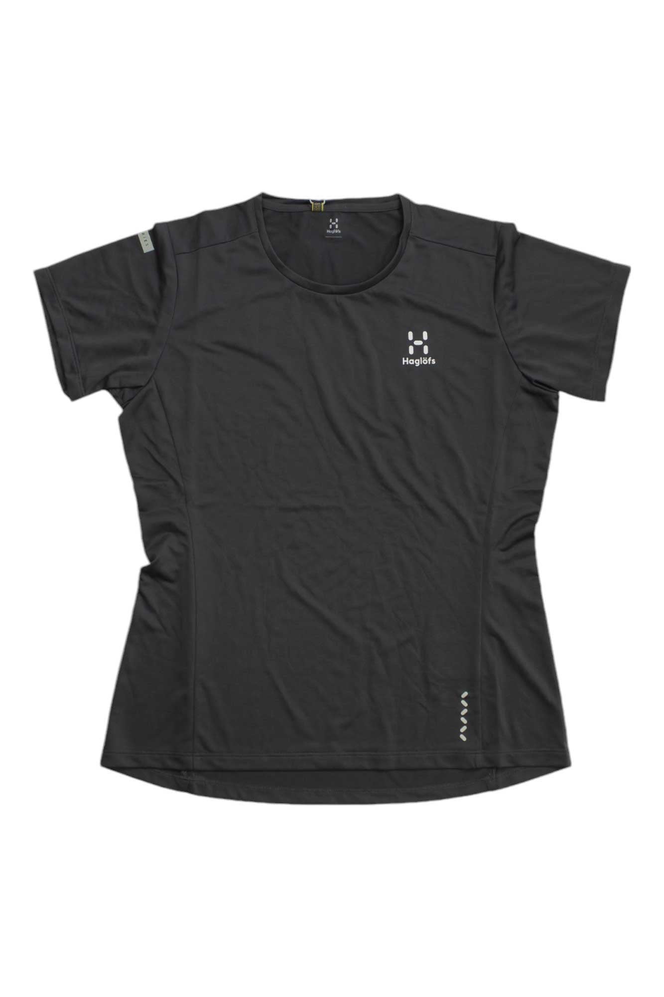 The Haglofs Womens L.I.M Tech Tee is a black, moisture-wicking hiking shirt for women, made from recycled polyester. It features short sleeves, a round neck, the Haglöfs logo on the left chest, and reflective accents near the hem.