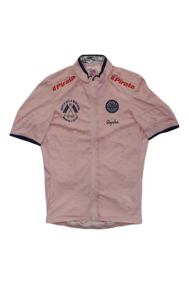 The Rapha Men’s Super Lightweight Jersey is light pink with short sleeves, a front zipper, and features dark blue and red logos and text including il Pirata, Rapha branding, and circular emblems on the chest.