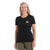 A smiling woman with long gray hair wears the Icebreaker Womens Merino 150 Tech Lite II Community SS Tee in black and olive green pants, standing against a white background. Ideal for hiking in comfort.