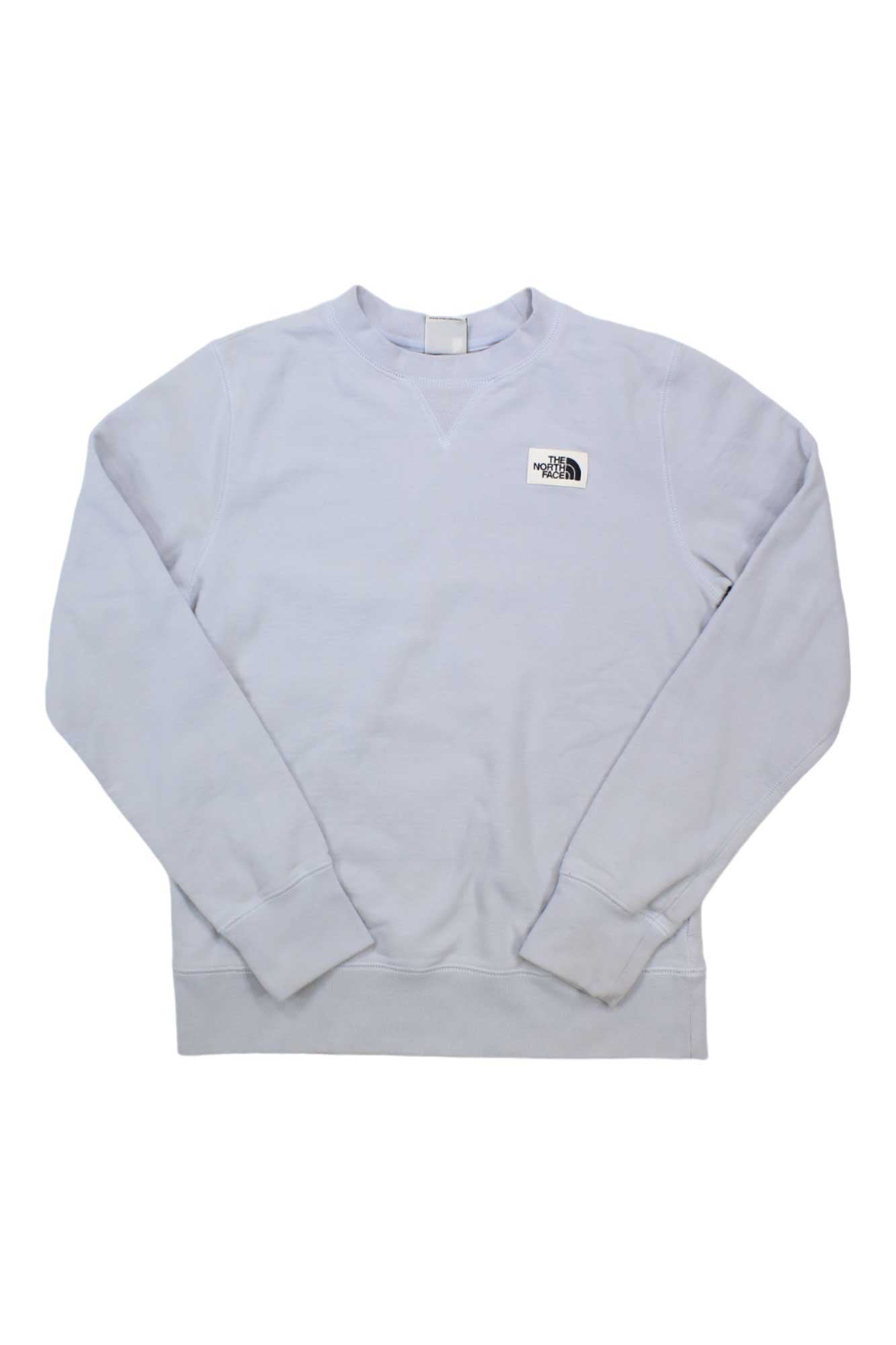 The North Face Womens Heritage Patch Crew, a light gray long-sleeve sweatshirt made from recycled fabric, features a small black and white logo on the left chest. The women's sweatshirt is shown laid flat on a white background.