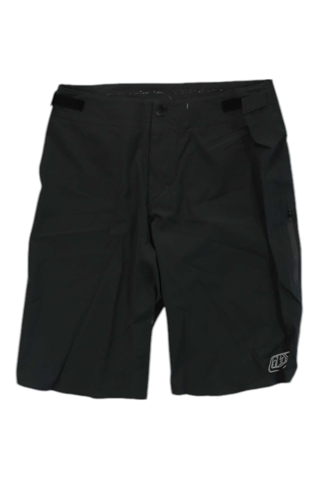 The Troy Lee Designs Mens Drift Short Shell is a black, knee-length short with button closure, side pocket, and a small logo on the lower left leg. Made from quick-dry, 4-way stretch fabric and shown against a white background.