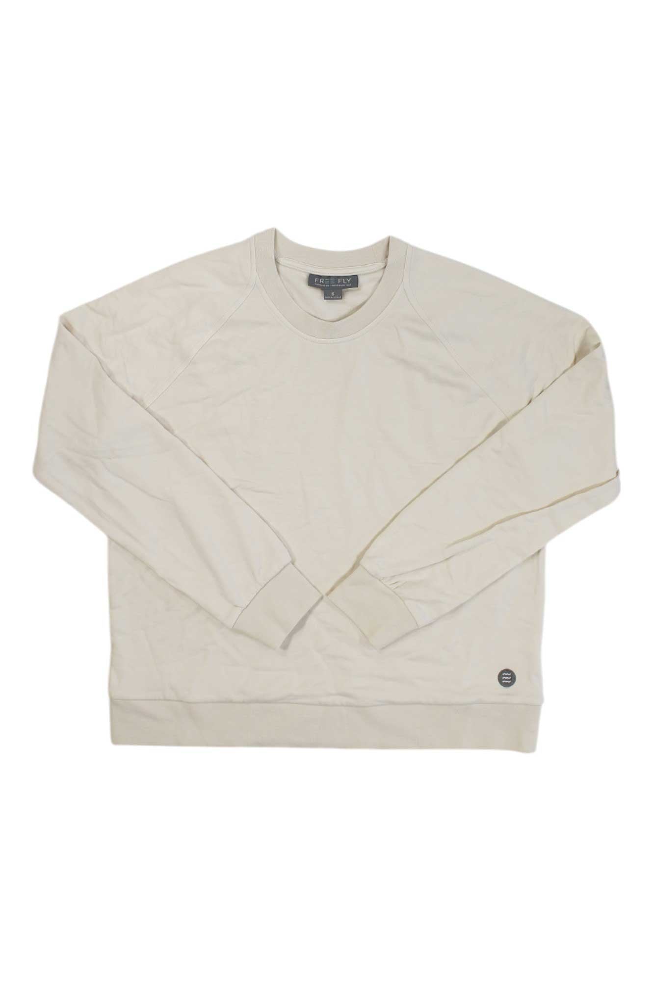 The Free Fly Womens Bamboo Lightweight Fleece Crew is a plain, long-sleeve, off-white crewneck sweatshirt with a small round logo on the bottom left hem and a visible neck tag, shown laid flat on a white background.