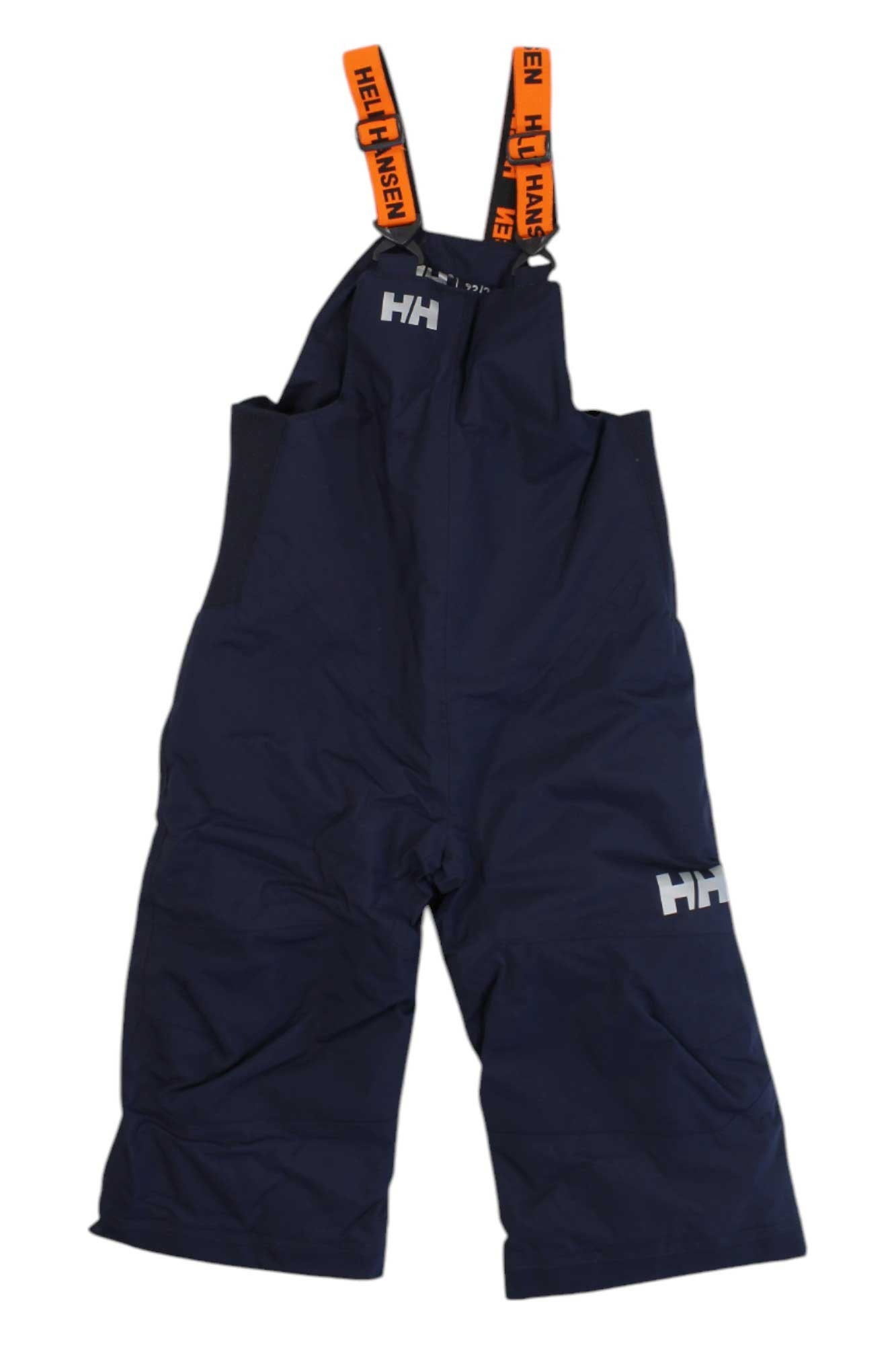 The Helly Hansen Kids Rider 2 Insulated Bib Pant features navy blue overalls with orange adjustable suspenders, HH logos on the chest and left thigh, a loose fit, and a waterproof boot gaiter for extra protection.