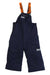 The Helly Hansen Kids Rider 2 Insulated Bib Pant features navy blue overalls with orange adjustable suspenders, HH logos on the chest and left thigh, a loose fit, and a waterproof boot gaiter for extra protection.