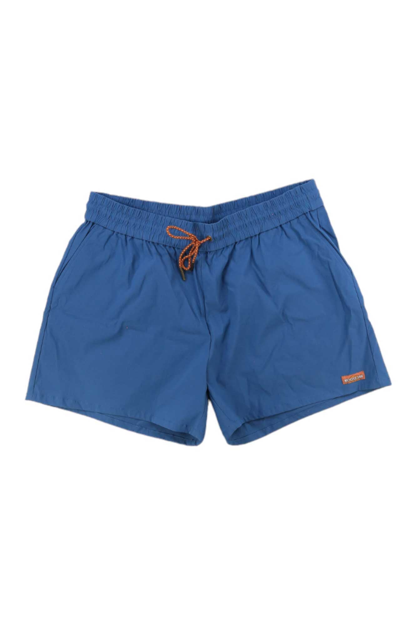 Moosejaw Womens THE Moosejaw Short: blue water-resistant shorts featuring an elastic waistband, orange drawstring, side pockets, and a small orange logo patch by the hem.