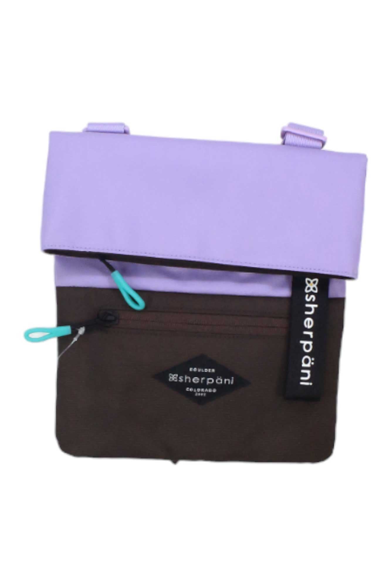 The Sherpani Womens Pica Cross Body Bag is a small bag made from recycled materials, featuring a lavender fold-over flap, brown zippered front pocket, turquoise zipper pull tabs, and a black Sherpani logo tag.