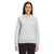 A woman faces forward in The North Face Womens Heritage Patch Crew, a light gray sweatshirt made from recycled fabric with a small left chest logo, paired with black pants against a plain white background.