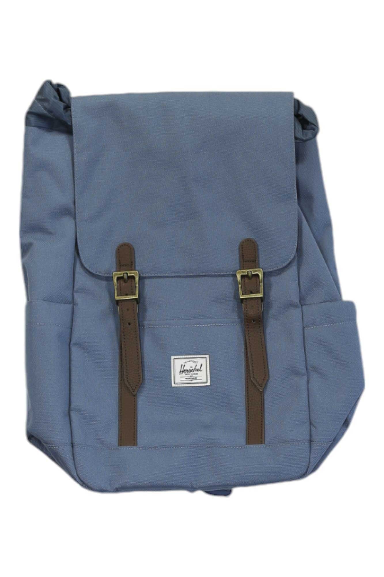 The Herschel Supply Company Retreat Small Backpack is blue with a flap closure, two brown buckle straps, side pockets, and a classic design. Made from EcoSystem recycled fabric, it has a white label and fits small laptops.