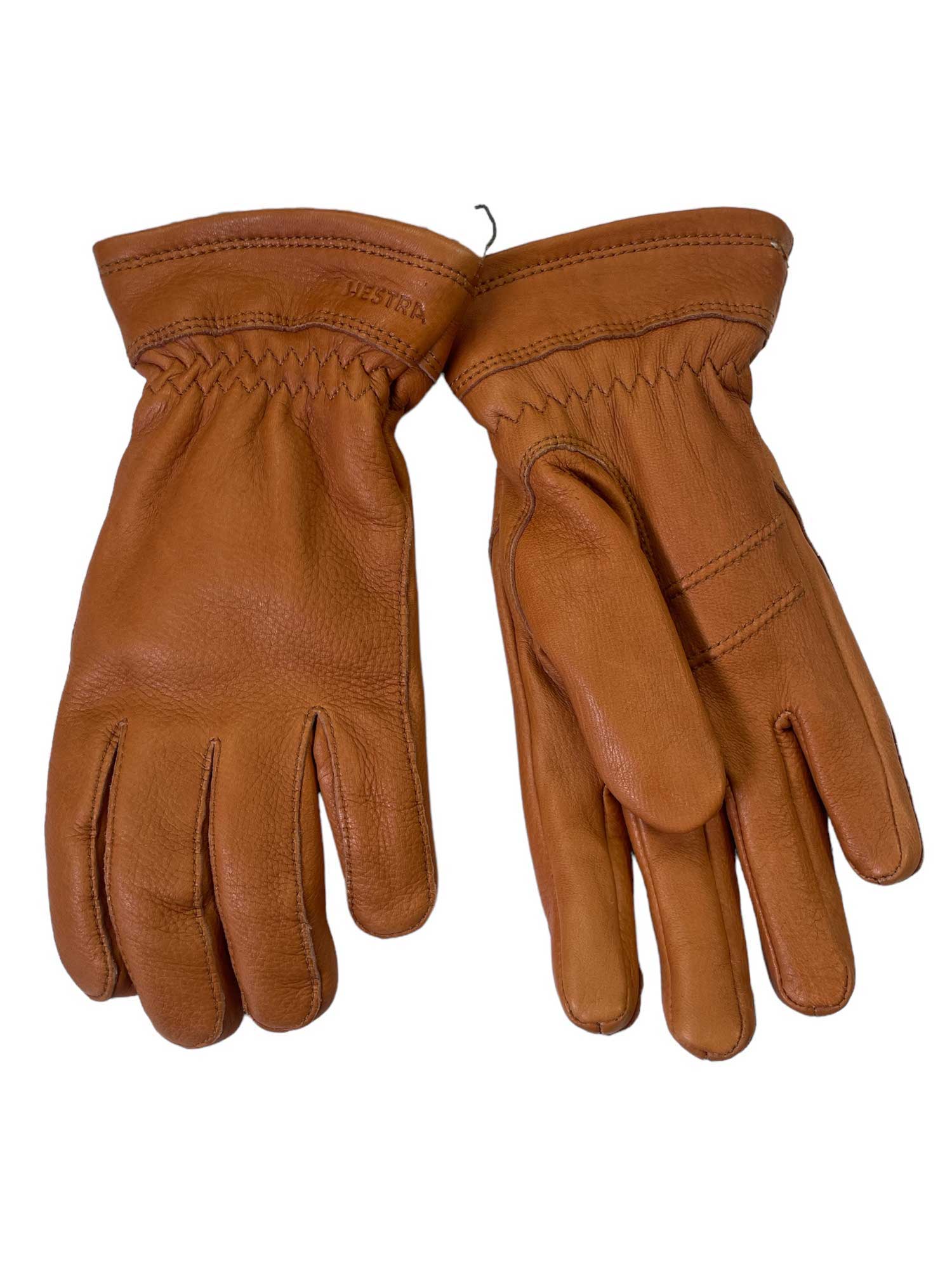 A pair of Hestra Womens Deerskin Primaloft Gloves in brown, featuring visible stitching and gathered elastic wrists, is laid flat on a white background.