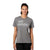A woman with dark hair in a ponytail smiles while wearing the Cotopaxi Womens Do Good SS Tee, a gray organic cotton shirt with bold white DO GOOD text, standing against a plain white background.