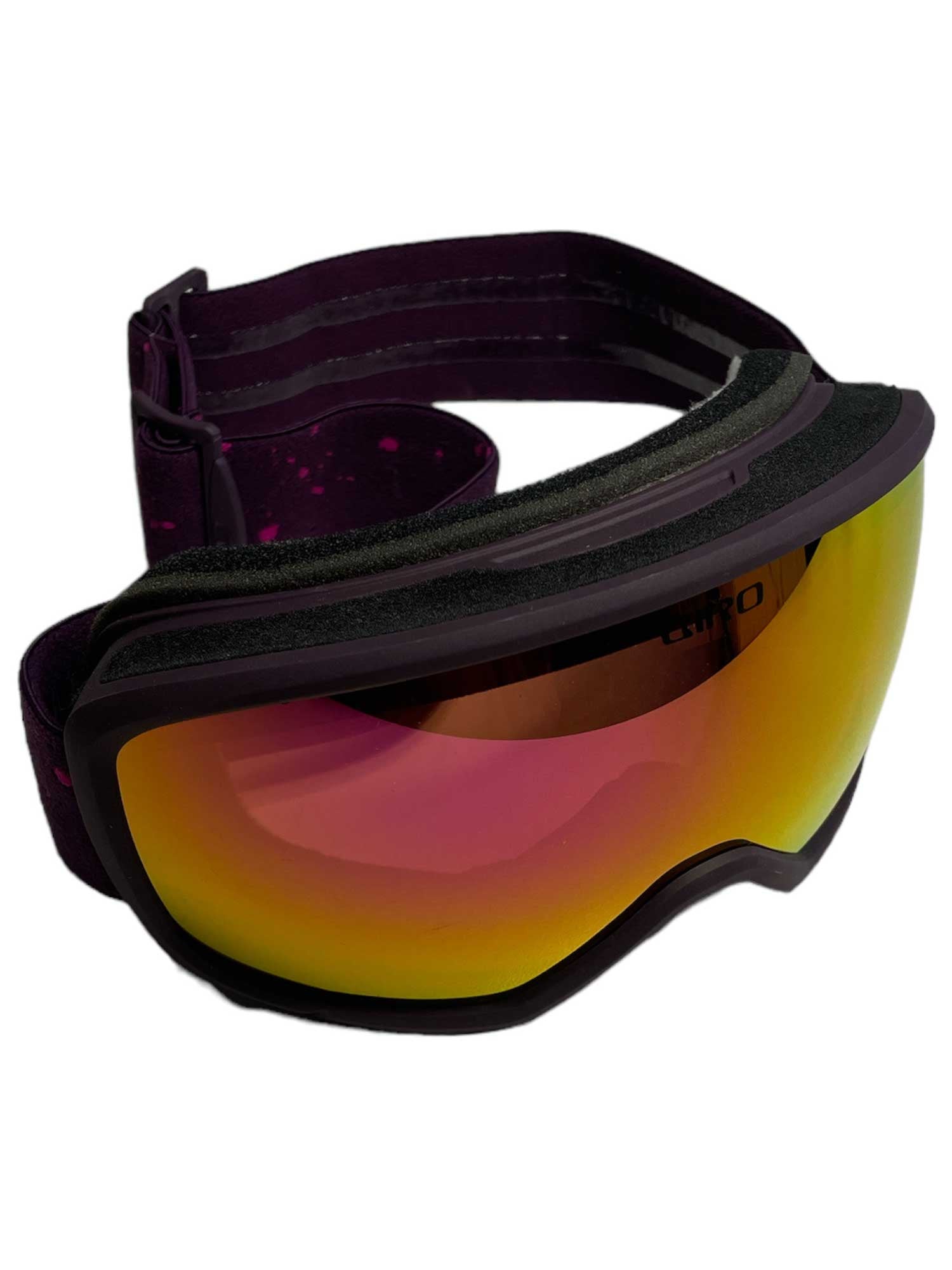 The Giro Women's Millie Goggle features a reflective red-orange lens and a black and purple adjustable strap. These OTG-friendly ski goggles are angled to display both the vibrant lens and stylish strap.