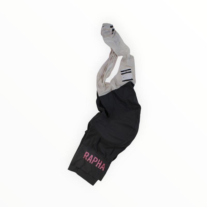 A pair of black and gray Rapha Mens Pro Team Bib Shorts II - Long with pink RAPHA branding on the leg, featuring a dual-density chamois pad, shown on a white background.