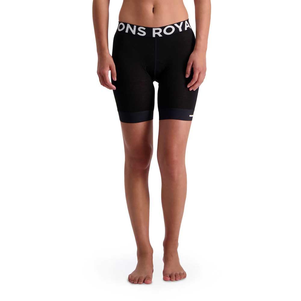 A woman stands barefoot wearing the Mons Royale Women's Enduro Bike Short Liner in black, featuring a wide elastic waistband with "Mons Royale" in white letters. The image is cropped from the waist down.
