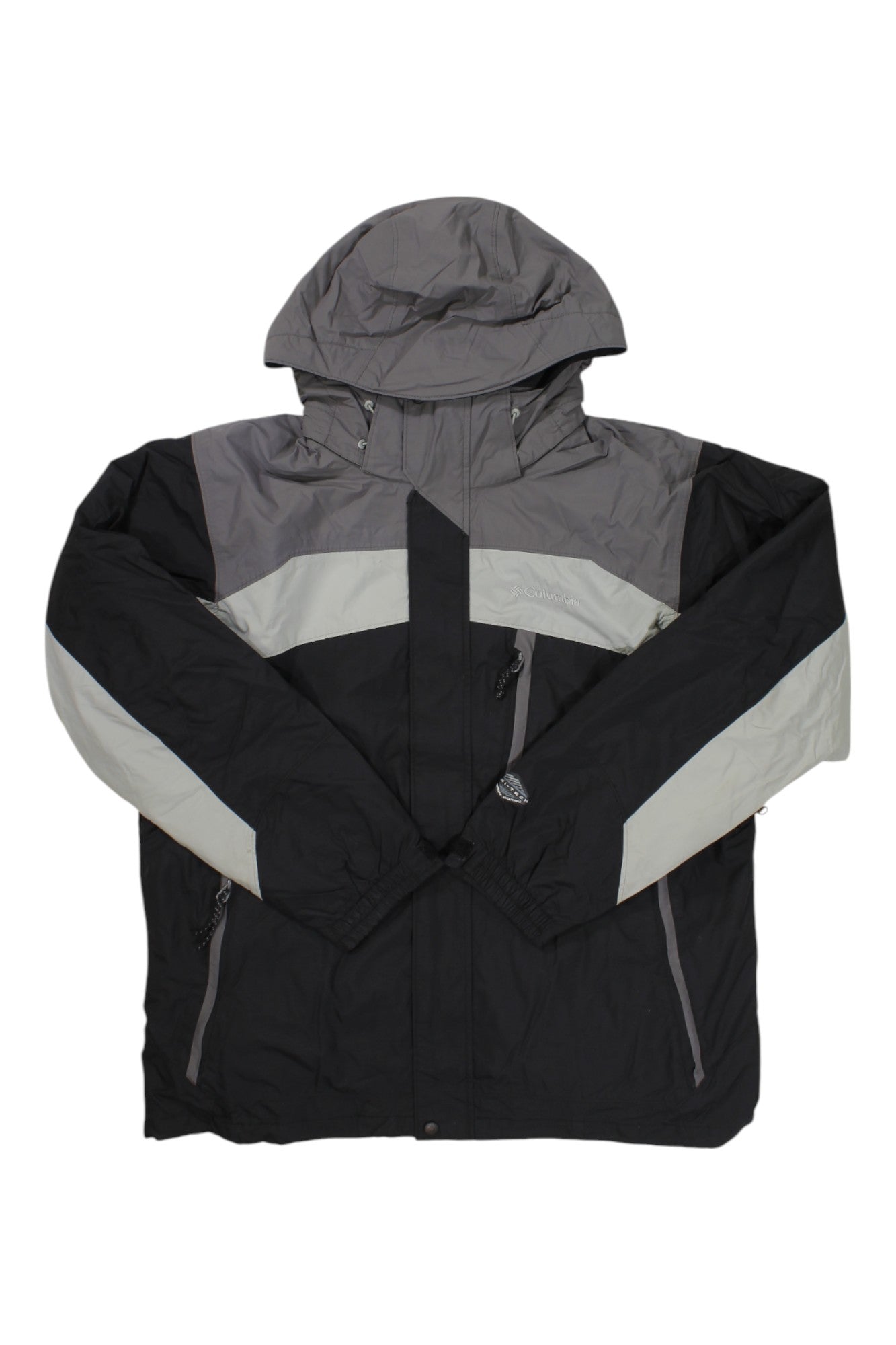 The Columbia Mens Whirlibird Interchange Jacket, a versatile black, gray, and white 3-in-1 men's winter jacket with zippered pockets and color-blocked design, is shown laid flat on a white background.