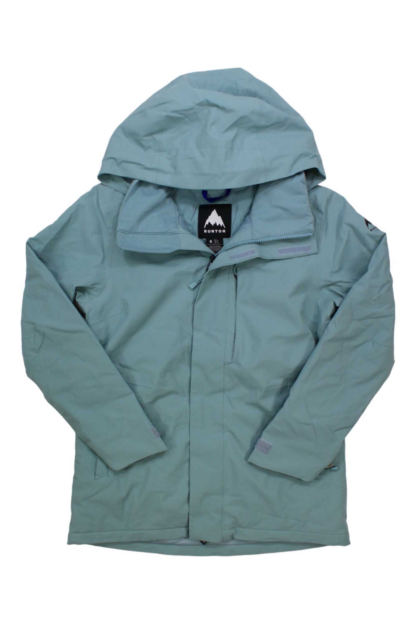 The Burton Womens Jet Ridge Jacket is a light blue shell laid flat with the front zipper partially open, revealing a black and white mountain logo on the inner tag. This lightweight, long-sleeve hiking jacket includes a chest pocket for outdoor adventures.