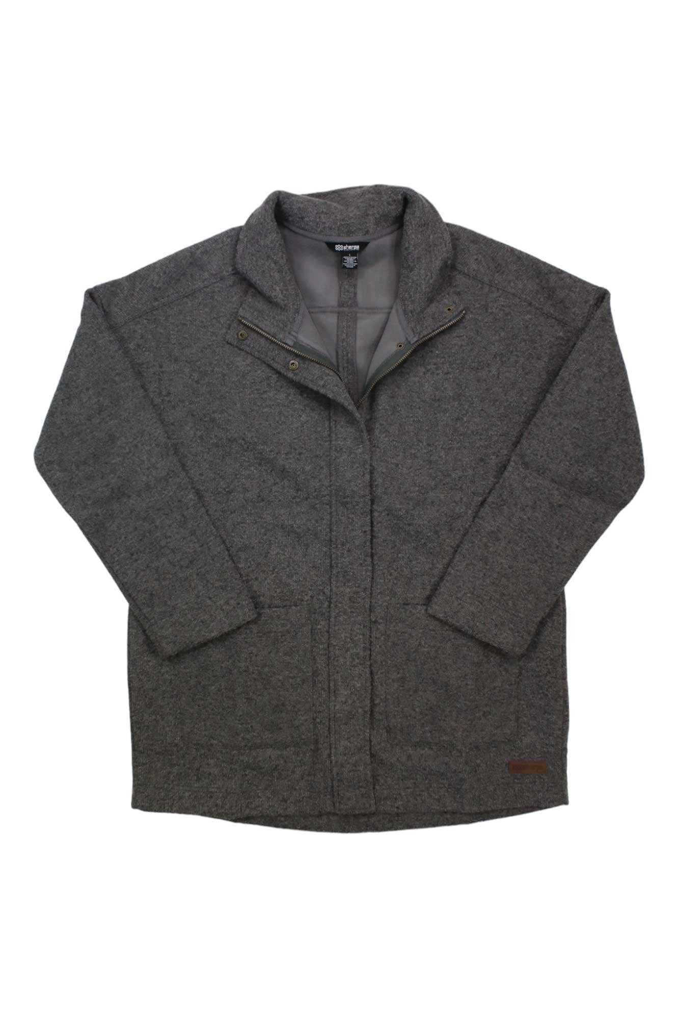 The Sherpa Womens Lhamu Coat is a gray, long-sleeve zip-up jacket with a high collar, front pockets, and a leather patch near the hem. Laid flat on a white background, it offers casual style and comfort.