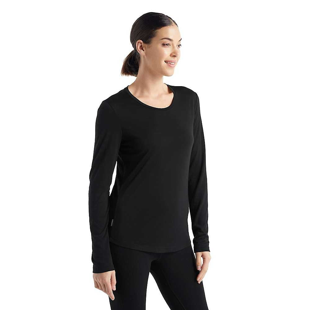 A woman with dark hair in a low ponytail wears the Icebreaker Womens Sphere II LS Tee and black leggings, smiling while looking to the side against a white background. The tee's moisture-wicking fabric ensures all-day comfort.