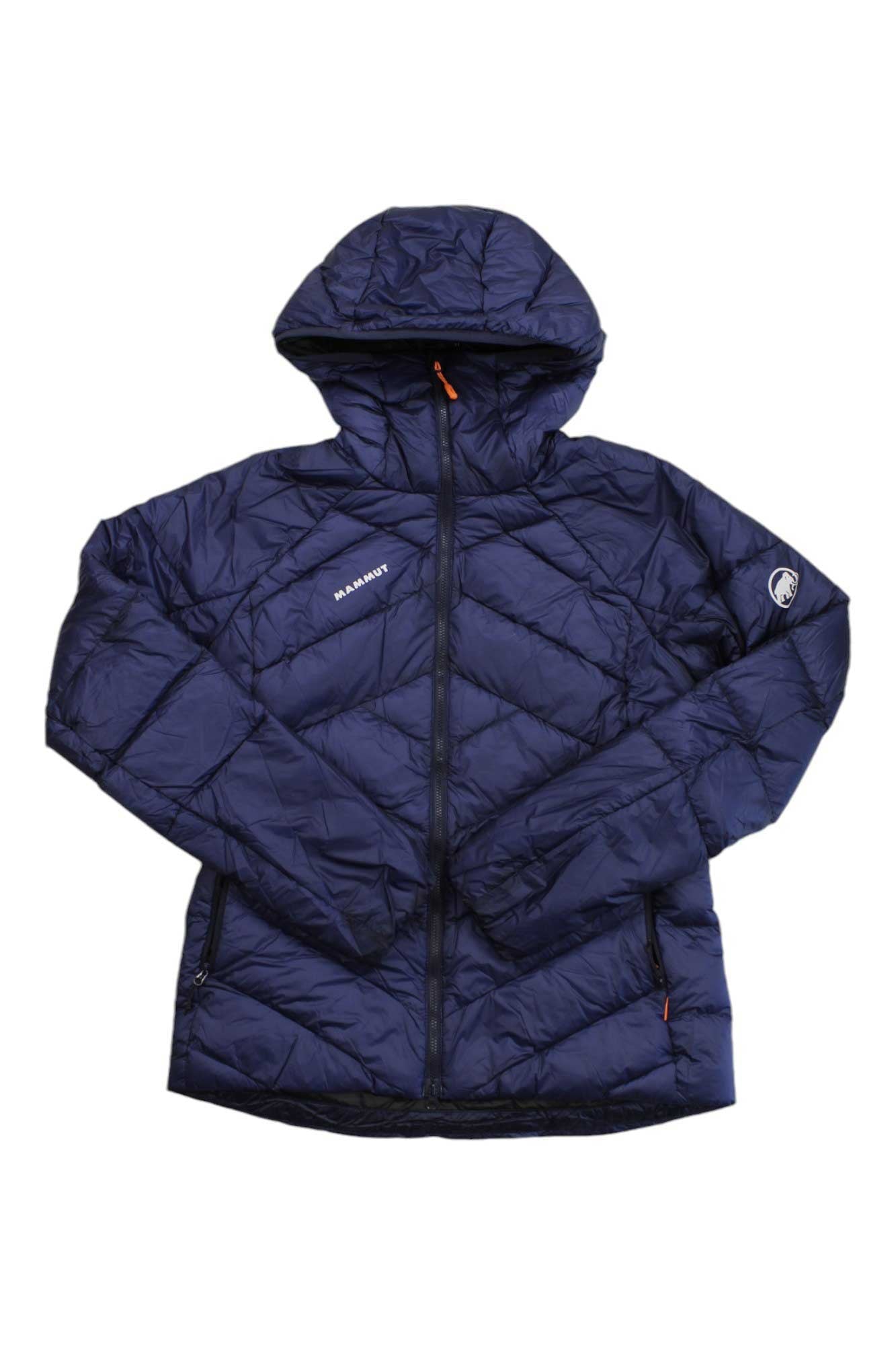 The Mammut Women's Taiss IN Hooded Jacket in navy blue features a hood, front zipper, and Mammut logos on the chest and sleeve. Displayed against a white background, this insulated puffer jacket combines warmth and style, making it an ideal choice for women's mountaineering and outdoor adventures.