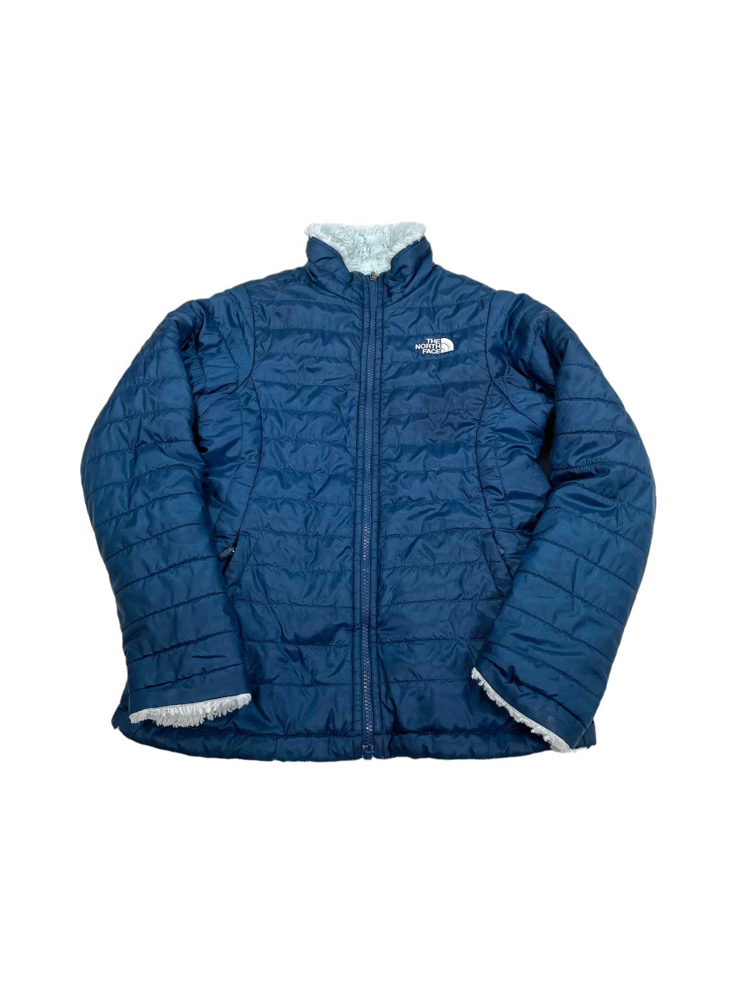 A blue Girls Reversible Mossbud Swirl Jacket by The North Face, with a front zipper, white fleece lining at the collar and cuffs, and Heatseeker Eco Insulation for warmth, shown on a white background.