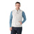 A man in a Smartwool Men's Hudson Trail Fleece Vest, layered over a blue long-sleeve shirt and dark jeans, smiles with one hand in his vest pocket against a plain white background.