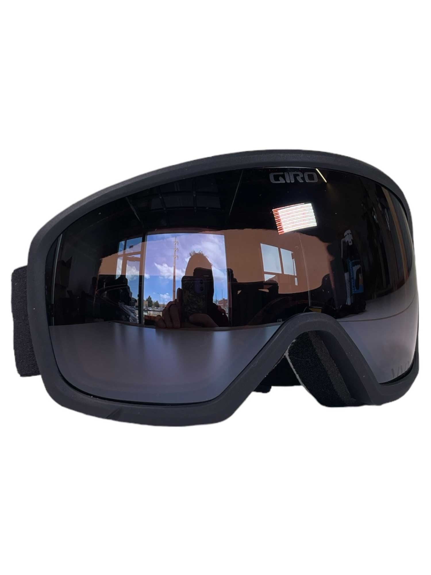 The Giro Women's Millie Goggle features a black frame with reflective lenses that show subtle reflections. These OTG-compatible goggles offer a wide, padded frame and an adjustable strap for comfortable wear on the slopes.