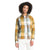 A woman with curly hair models The North Face Women's Berkeley LS Girlfriend Shirt, a long sleeve plaid shirt in yellow, white, blue, and tan, paired with white pants against a plain white background.
