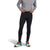 A person wearing The North Face Mens Winter Warm Essential Legging in black and a gray long-sleeve shirt stands against a white background, adjusting the waistband of the leggings.