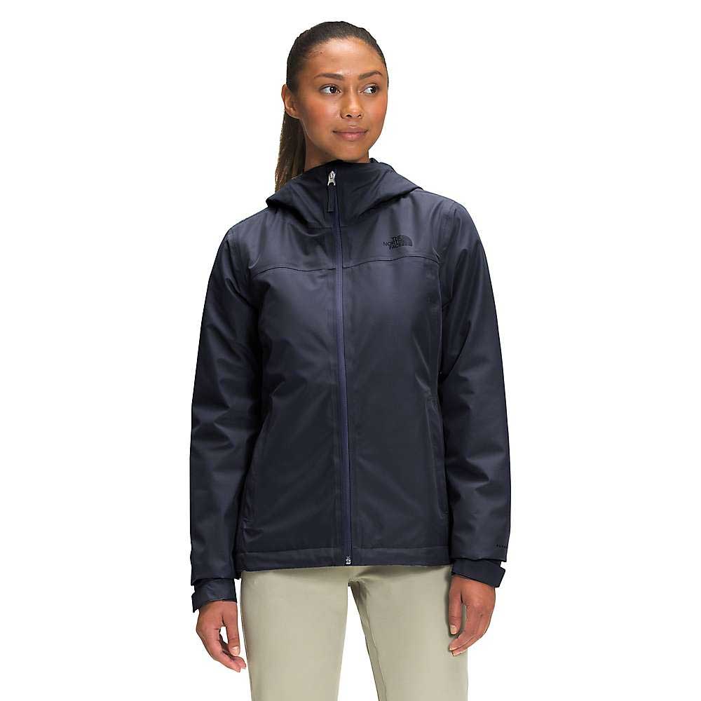 A woman stands facing forward with her hair tied back, wearing The North Face Womens Dryzzle FUTURELIGHT Insulated Jacket in dark navy and light-colored pants.