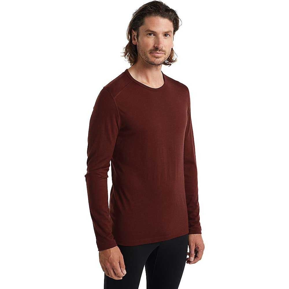 A man with shoulder-length brown hair wears the Icebreaker Mens 200 Oasis LS Crewe Top and black pants, standing against a plain white background and looking at the camera—a great example of effortless men's baselayer style.