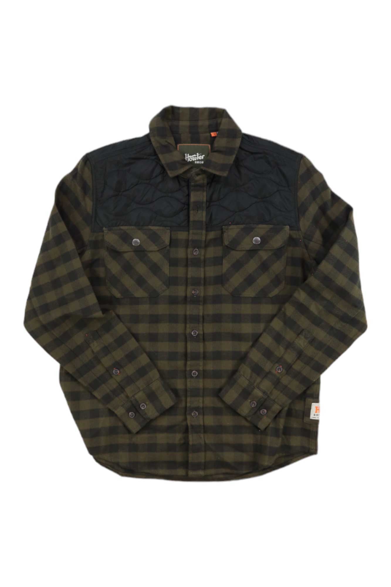 The Howler Brothers Mens Quintana Quilted Flannel Shirt features a green and black plaid cotton flannel, black quilted shoulder panels, two chest pockets with button flaps, and a small white tag on the lower side. Laid flat on white background.