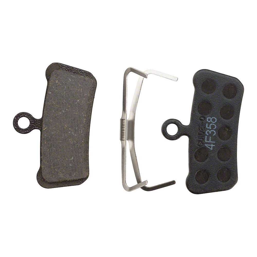 The SRAM Guide and Avid Trail Disc Brake Pads set includes a pad with friction material, a metal spring clip, and a sintered backing plate with circular indentations—perfect for trail biking.