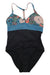 The Carve Designs Womens Dahlia One Piece swimsuit features a black bottom, solid blue waistband, floral top in blue, beige, green, and orange, adjustable straps for comfort, and a small front cutout.