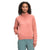 A woman with curly hair wears The North Face Women's Longs Peak Quilted 1/4 Zip Jacket in pink and teal pants, standing with one hand in her pocket and smiling slightly at the camera against a plain white background.