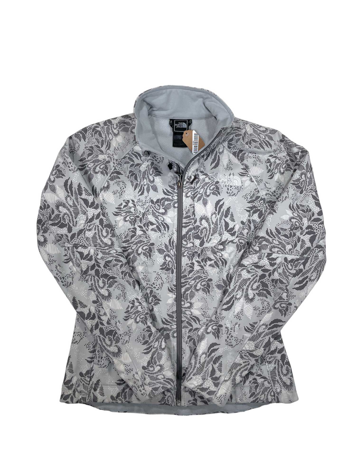 The Womens Apex Bionic Soft-Shell Jacket in light gray features an all-over dark gray floral and leafy design, a high collar, and windproof fabric. The jacket is displayed flat on a white background.