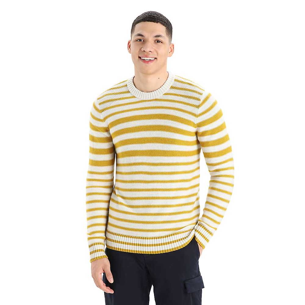 A smiling person wears the Icebreaker Mens Waypoint Crewe Sweater in yellow and white stripes with dark pants, standing against a plain white background.