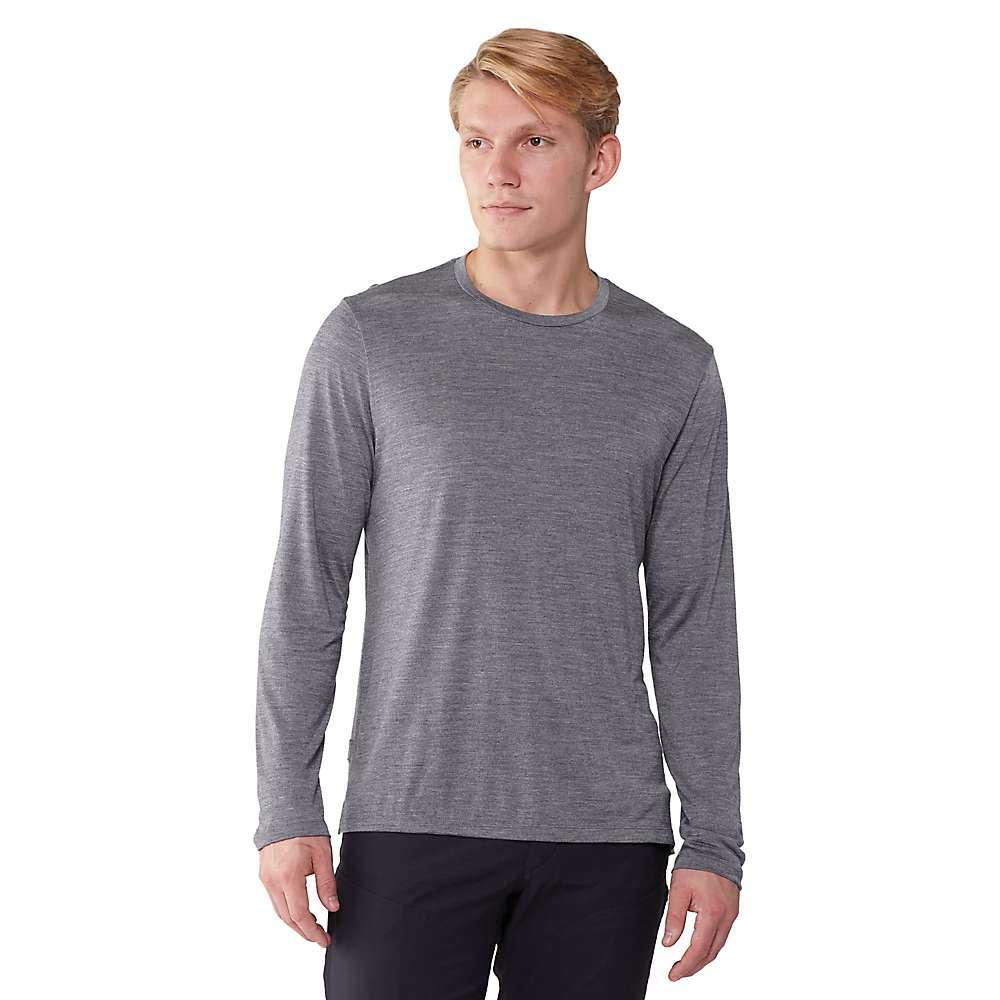 A person wears the Icebreaker Mens Sphere II LS Tee in heather gray with black pants, standing against a plain white background and looking slightly to the side with a neutral expression.
