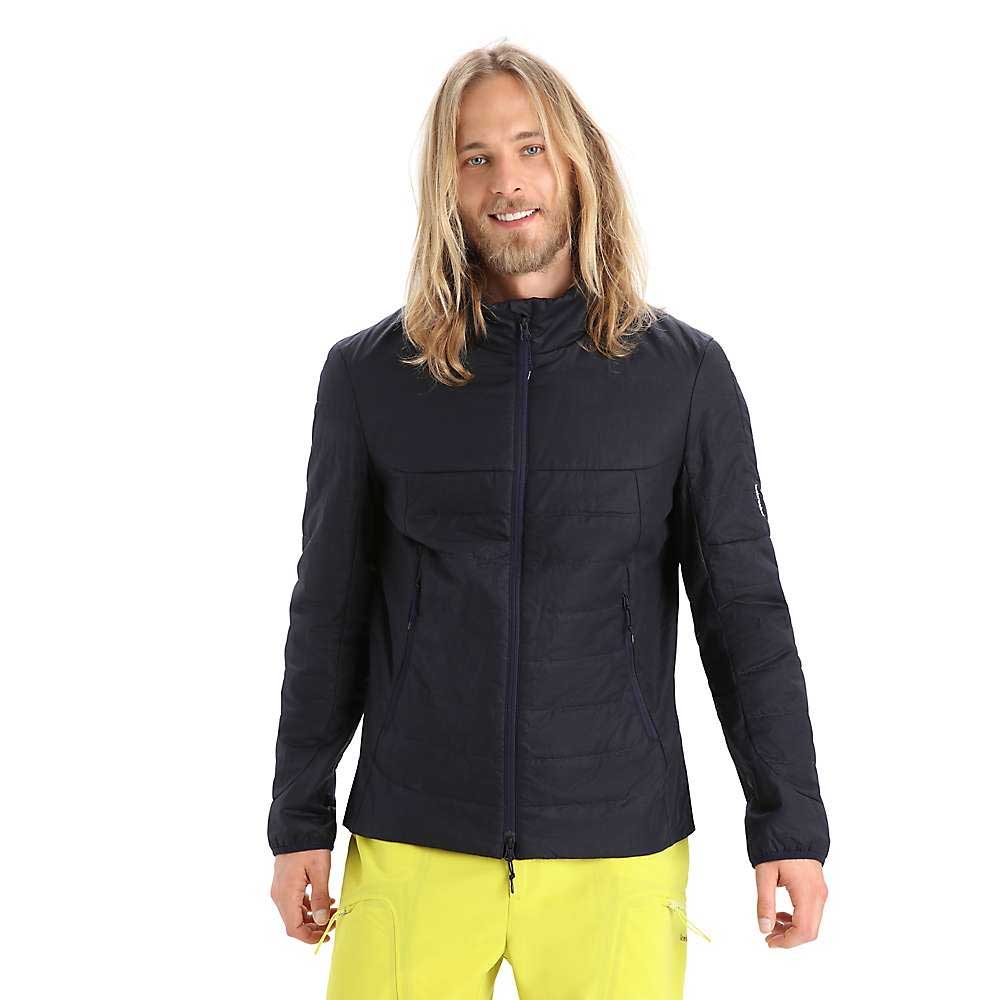 A man with long blonde hair wears the Icebreaker Mens Merinoloft Jacket in black and bright yellow pants, standing facing forward and smiling against a plain white background.