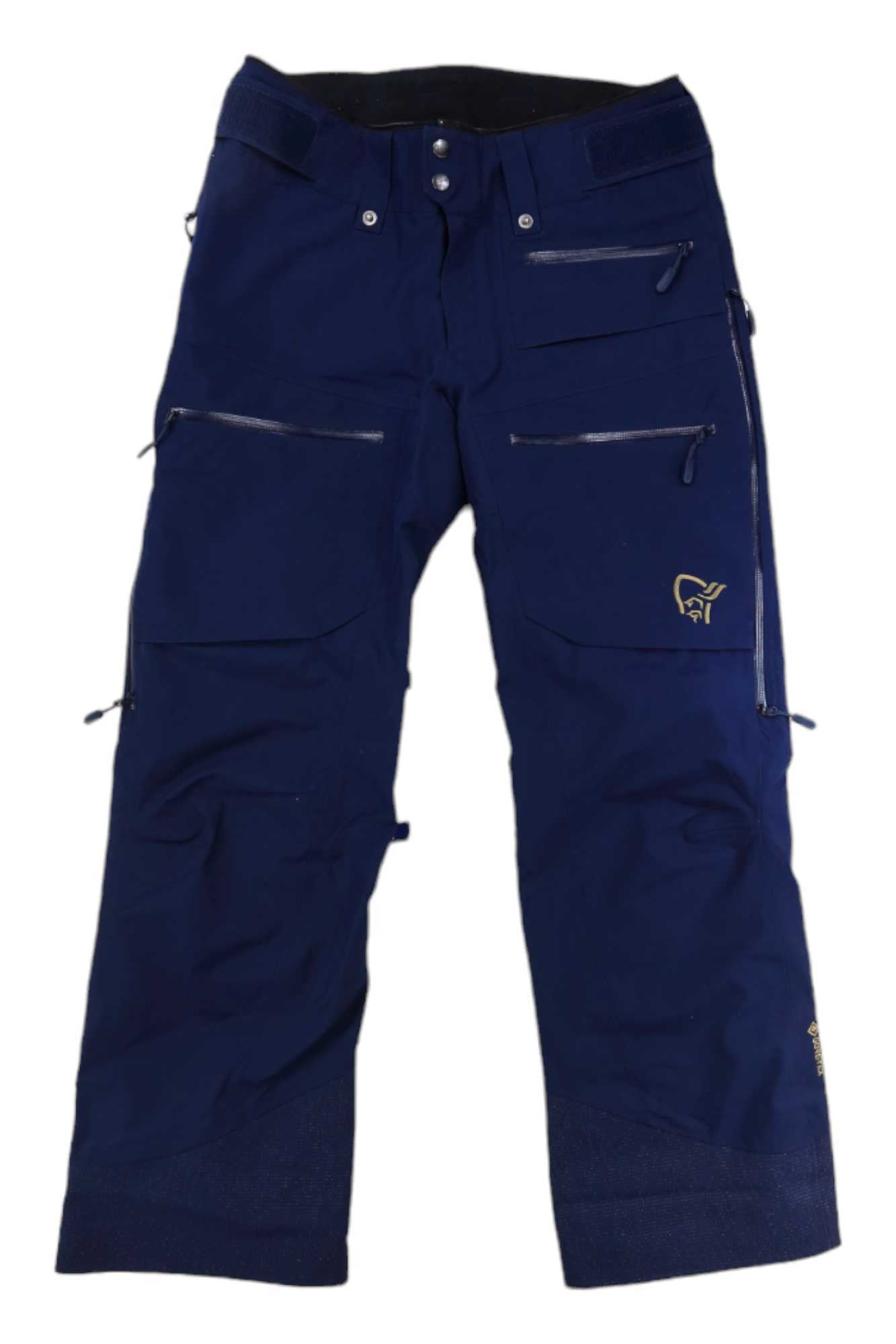 The Norrona Womens Lofoten GORE-TEX Insulated Snow Pants are dark blue with multiple zippered pockets, waist buttons, and a small yellow logo on the left leg. Made from durable, weather-resistant material for snowboarding.