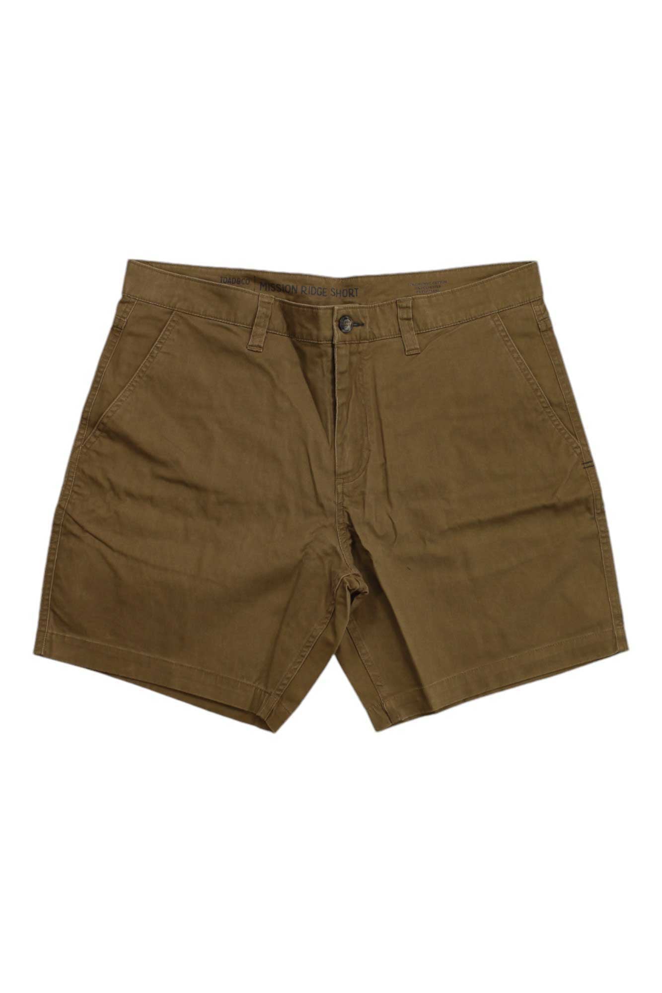 The Toad & Co Men's Mission Ridge 8 Inch Short is a pair of brown, knee-length hiking shorts made from organic cotton with side pockets and a button-zipper closure, shown laid flat on a white background.