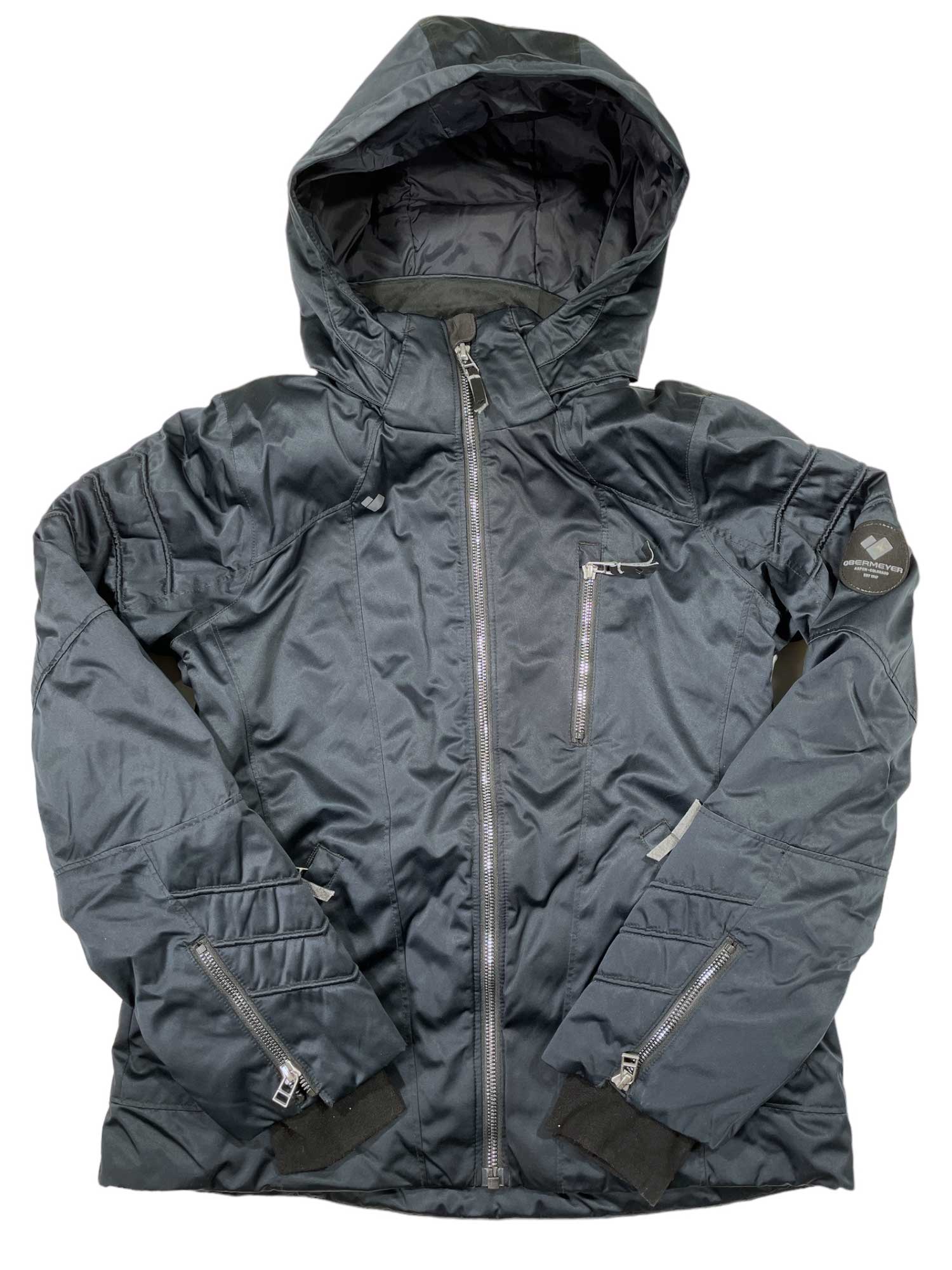 The Obermeyer Girls Rayla Ski Jacket in black features multiple zip pockets, adjustable cuffs, and a shiny finish. This insulated kids’ winter jacket keeps girls warm and stylish in cold weather.