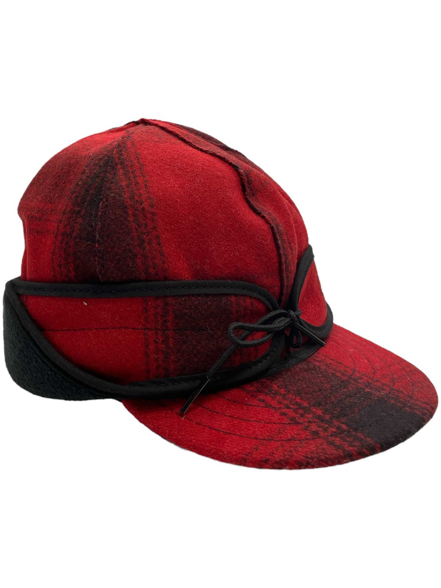 The Stormy Kromer Rancher Cap is a red and black plaid wool hat with ear flaps, black trim, and a front bow. Made in the USA with Thinsulate Insulation for added warmth.