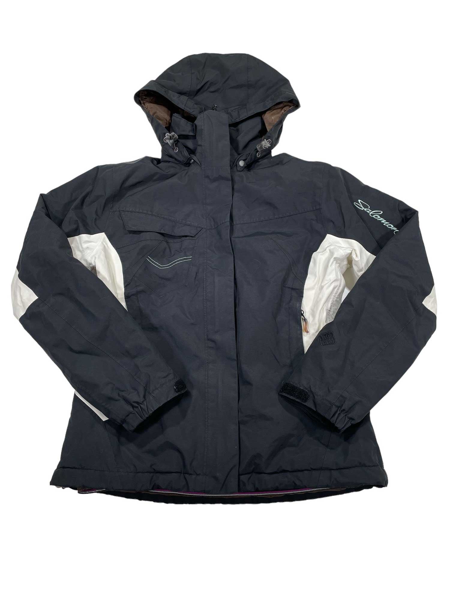 The Juniors Ski Jacket by Salomon is black with white side and arm accents, a zippered front, chest pocket, left sleeve logo embroidery, and insulation to keep you warm and stylish all winter.