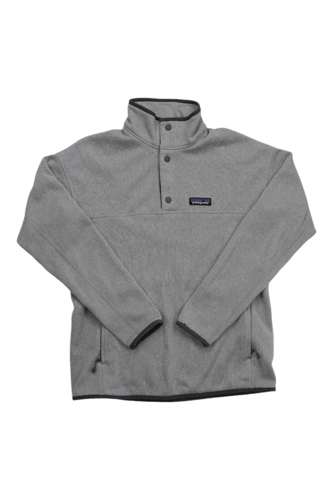 The Women's Lightweight Better Sweater Marsupial Pullover is a light gray, Fair Trade Certified polyester fleece with a stand-up collar, snap placket, small Patagonia logo, long sleeves, and two zippered side pockets.