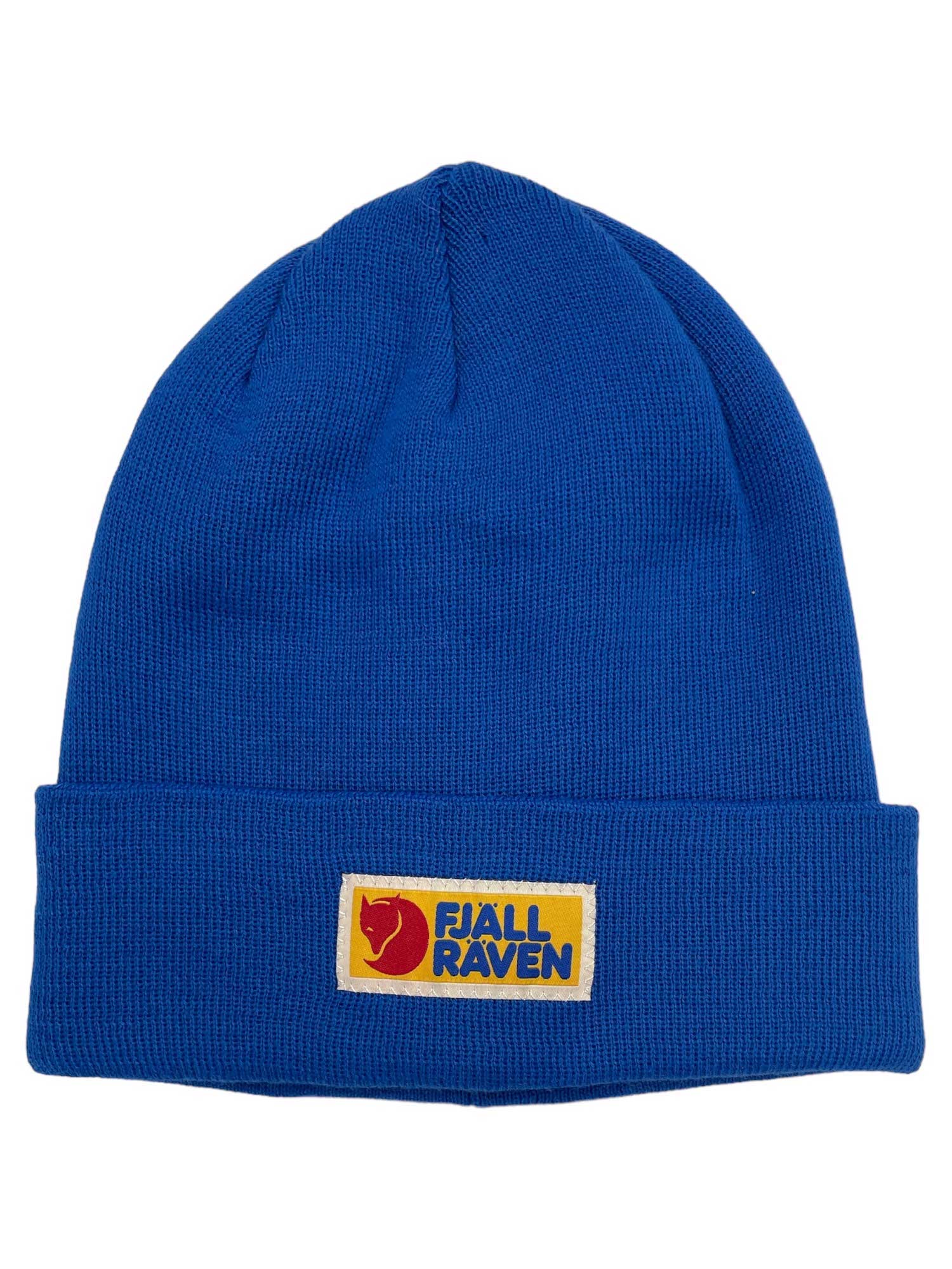 The Fjallraven Vardag Classic Beanie is a bright blue knit hat with a folded brim and a rectangular yellow patch featuring the Fjällräven logo in red and blue on the front.