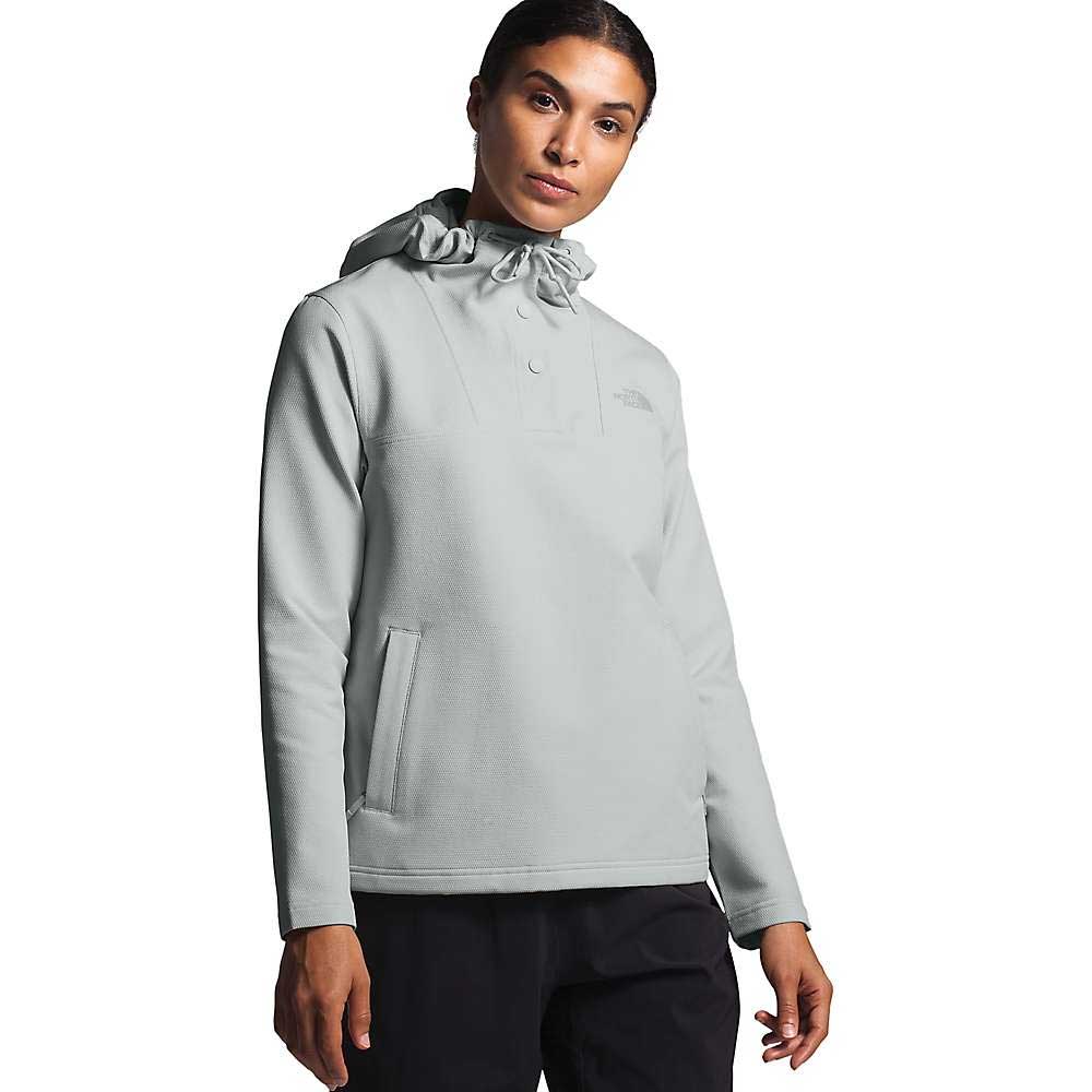 A woman in The North Face Womens Tekno Ridge Pullover Hoodie in light gray with a front pocket and black pants stands facing forward against a plain white background.