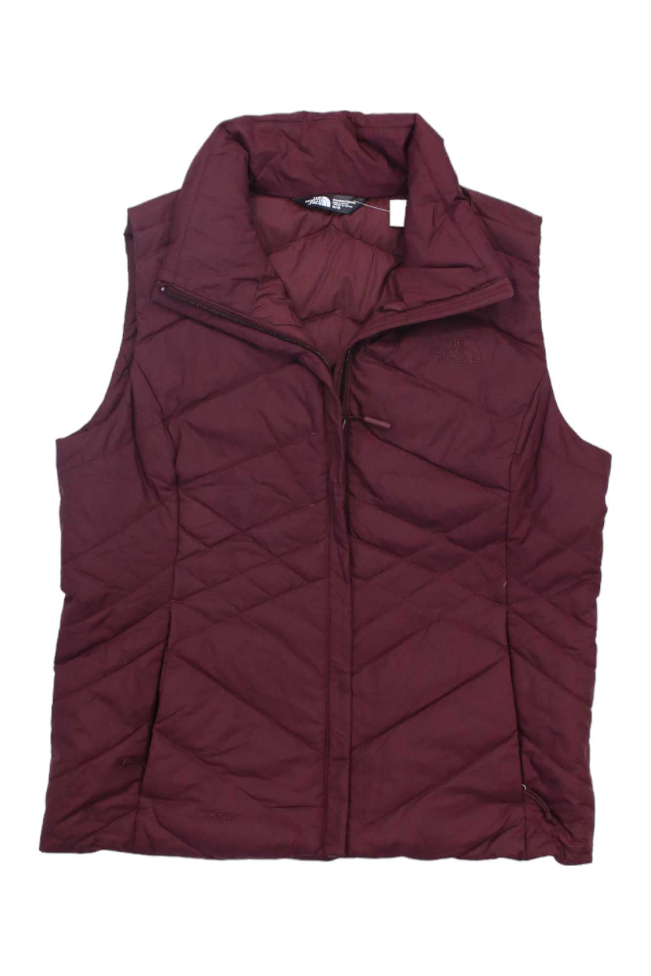 The North Face Womens Aconcagua Vest in maroon or burgundy features recycled synthetic insulation, a high collar, and zip closure. This wind-resistant vest is shown flat on a white background.