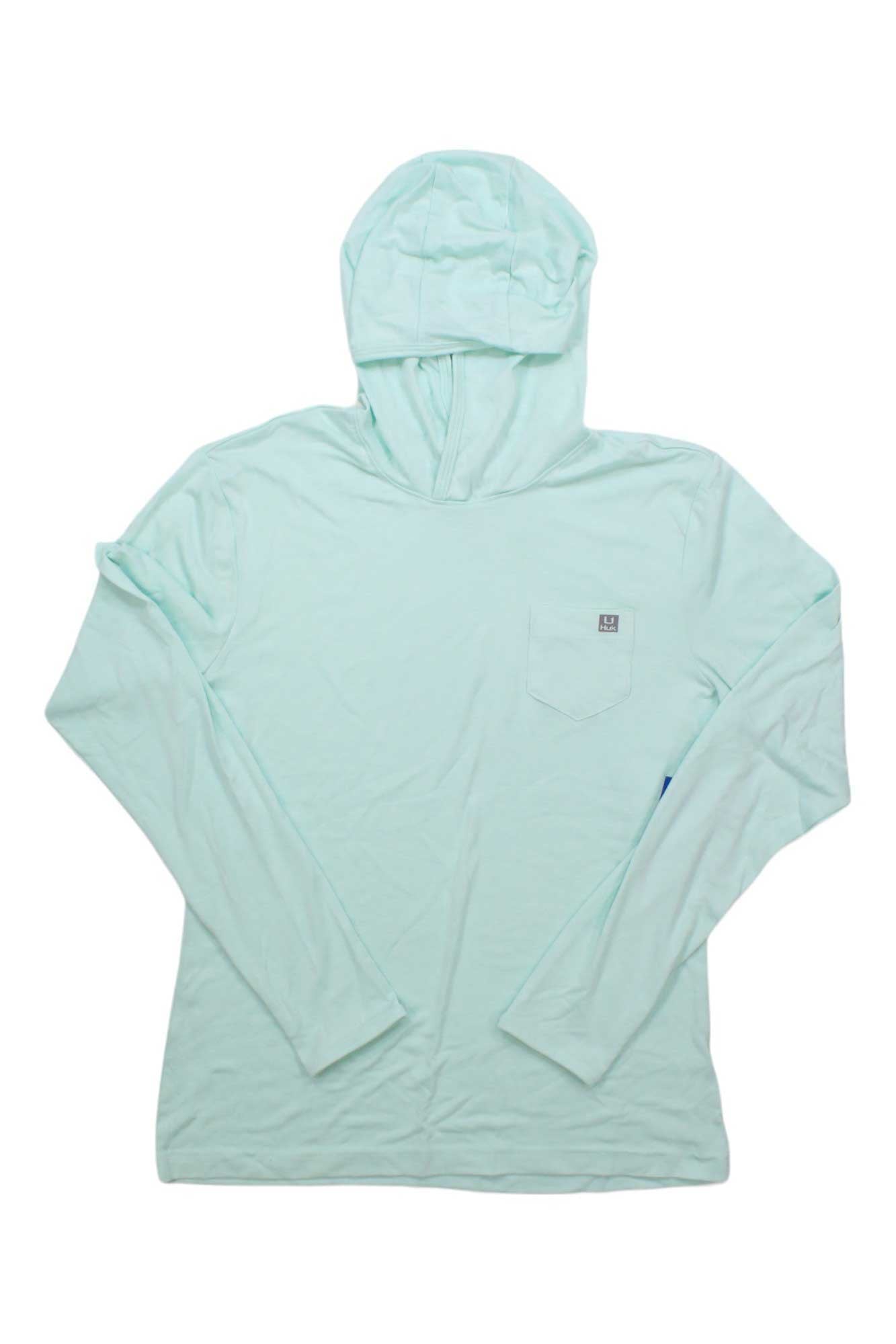 The Huk Womens Waypoint Hoodie is a light blue long-sleeve fishing hoodie for women, featuring a front chest pocket and made from recycled polyester for sustainability. Shown flat on a white background.