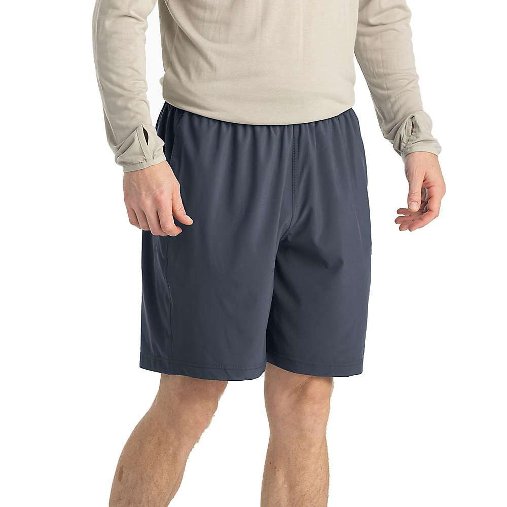 A person wearing a light long-sleeve shirt and the Free Fly Men's Breeze 8 Inch Short with UPF 50+ protection stands with hands relaxed at their sides, shown from shoulders to knees against a plain background.