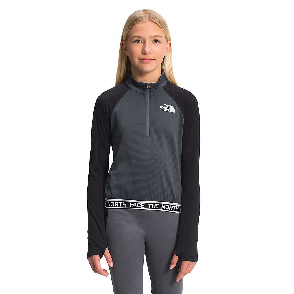 A young girl with straight blonde hair wears The North Face Girls Reactor Thermal 1/4 Zip Top with matching leggings, standing against a white background.