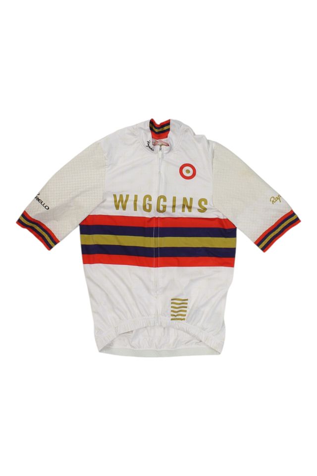 The Pro Team Aero Jersey II is a white cycling jersey featuring WIGGINS in gold, red, blue, and yellow stripes, a red target on the chest, and sleeve logos with gold trim on the cuffs.